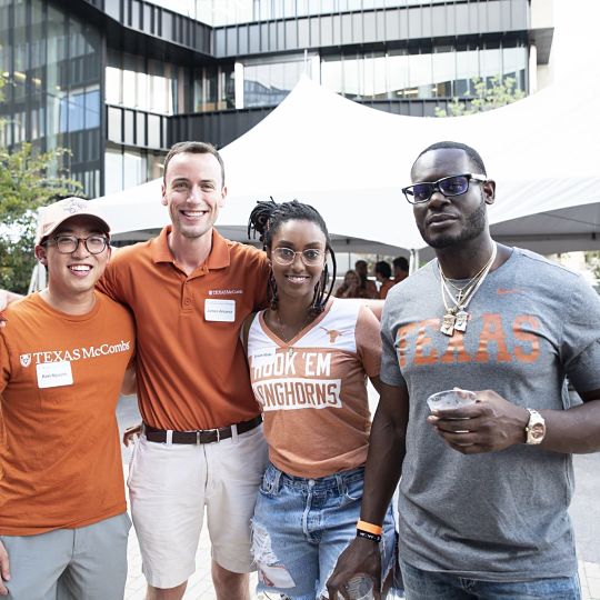 Four McCombs alumni pose for a picture at a tailgate