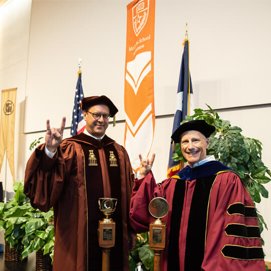 Two McCombs professors give hook em horns in commencement regalia