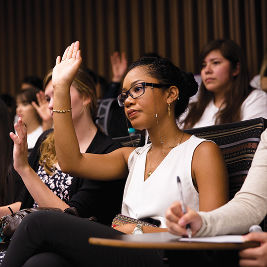 Several students with hands raised in class