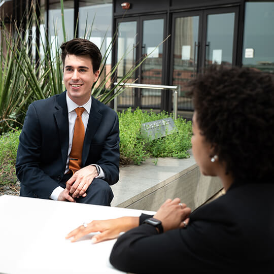 Three business casual students speak at a table