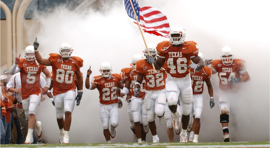 UT football players charge field through smoke with flag