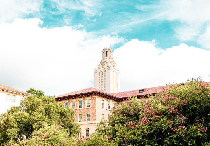 Top of University of Texas tower peeking over campus building