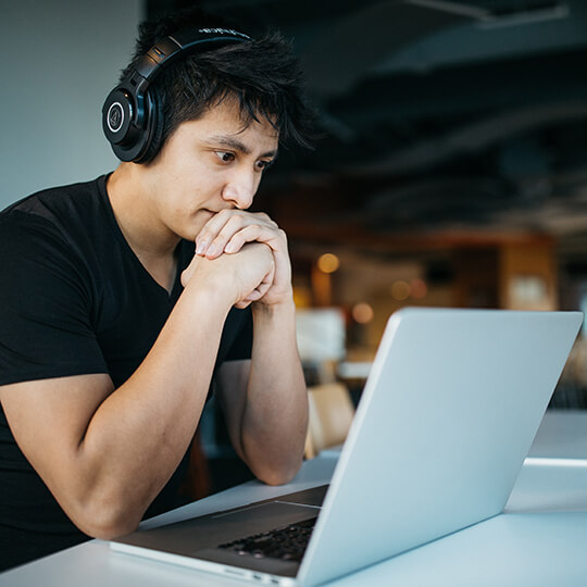 Person wearing headphones looking at a laptop