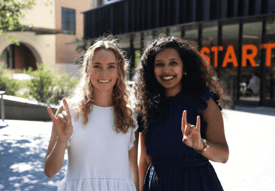 Hildebrand MBA at Texas McCombs MBA students outside of Rowling Hall showing school spirit with a hook 'em