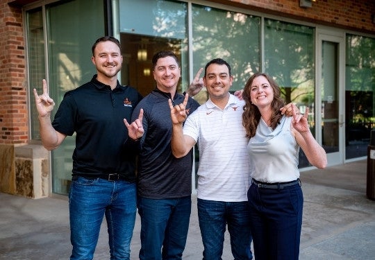 Texas McCombs Working Professional MBA McCombs Ambassador Committee team group picture and showing school spirit with a hook 'em