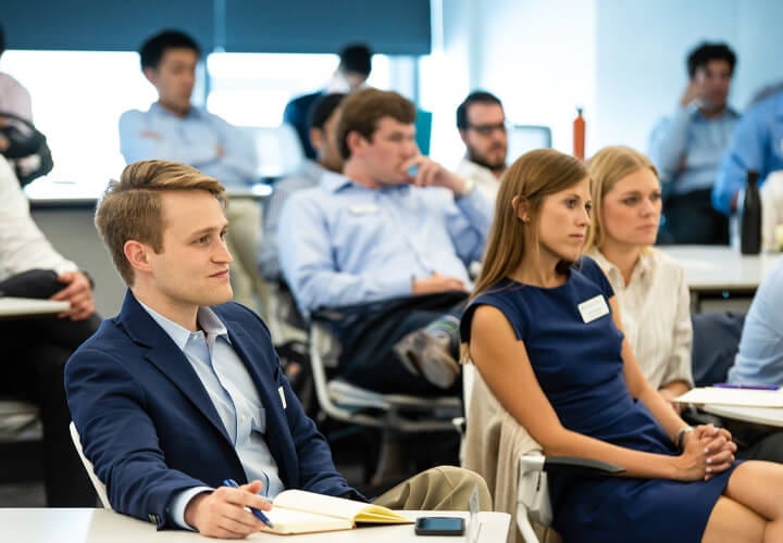 Texas McCombs MBA students taking notes and listening to a lecture in class