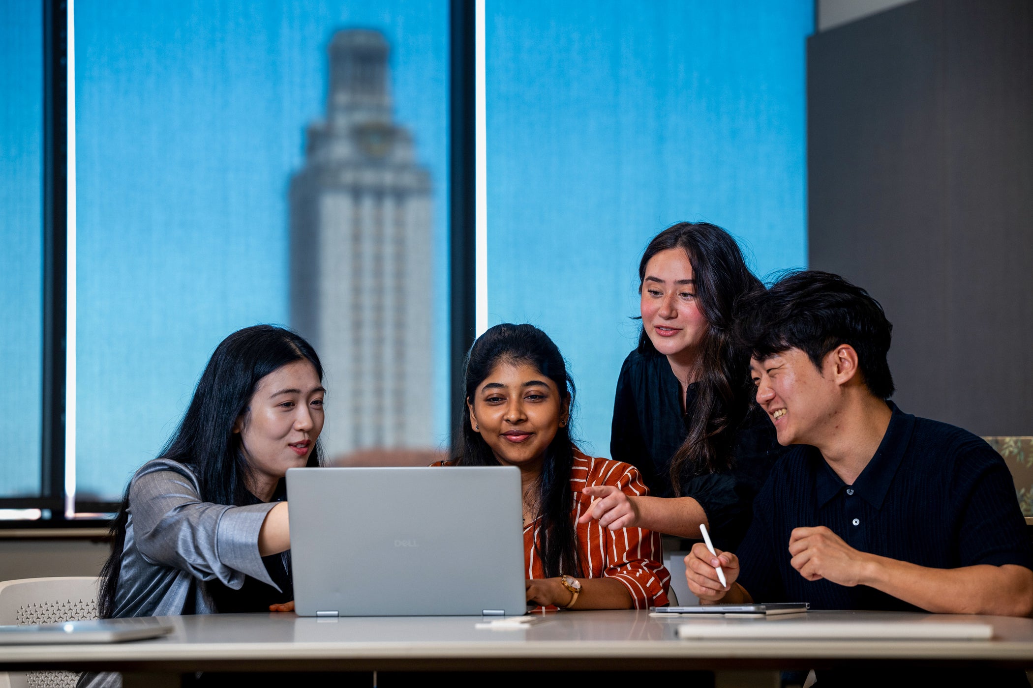 Four MSITM students working in a classroom with The Tower in the background