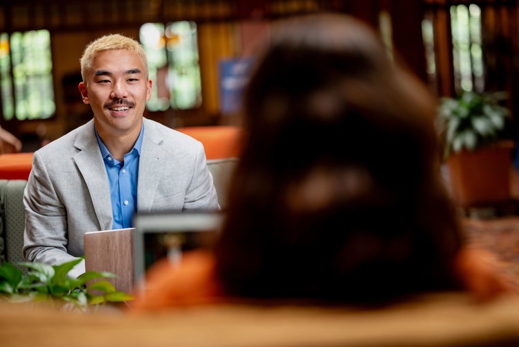Two people talking at a table with a laptop