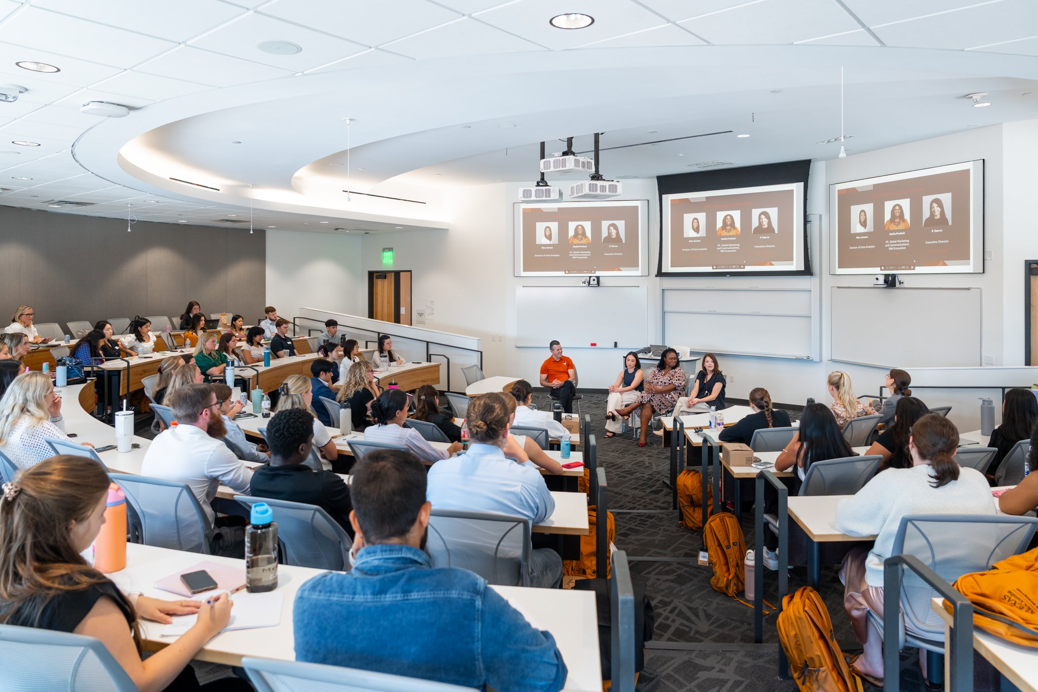 Classroom full of students with panel of 3 at front