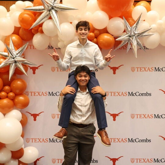 Two students posing with McCombs balloons