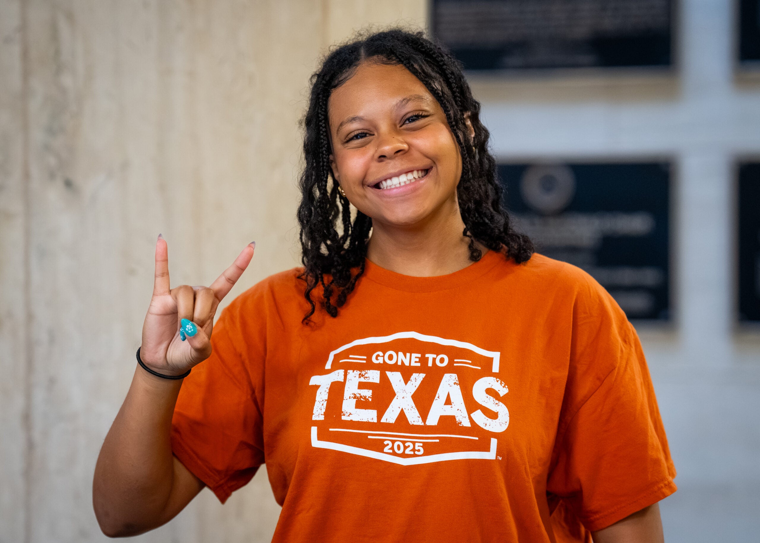 Student smiling and giving Hook 'Em Horns